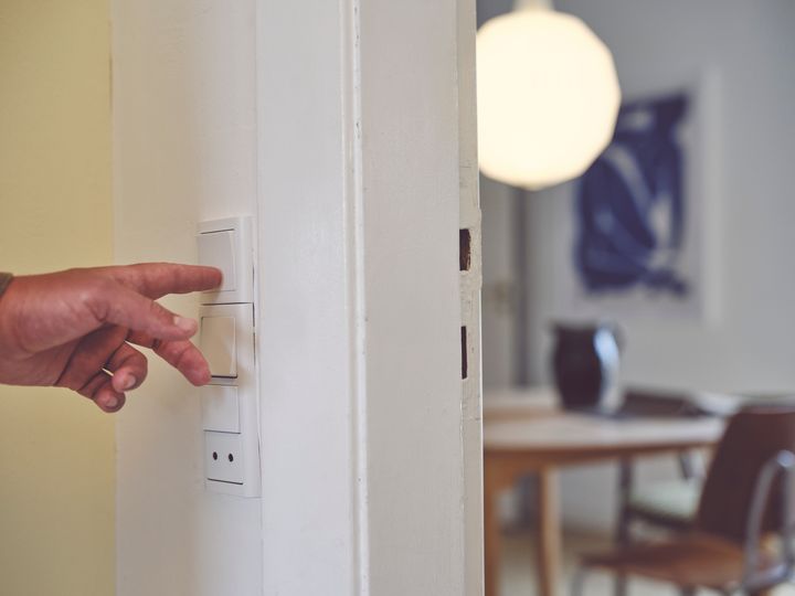 En person slukker lyset på en kontakt i hjemmet for at spare strøm og udnytte de billige timer med negative elpriser.