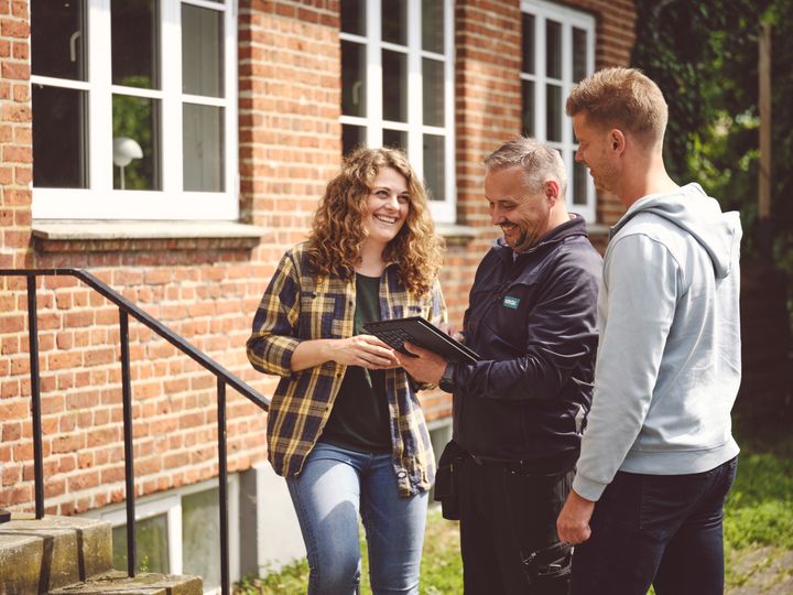 NRGi-medarbejder taler med to personer om et projekt ved en bygning.