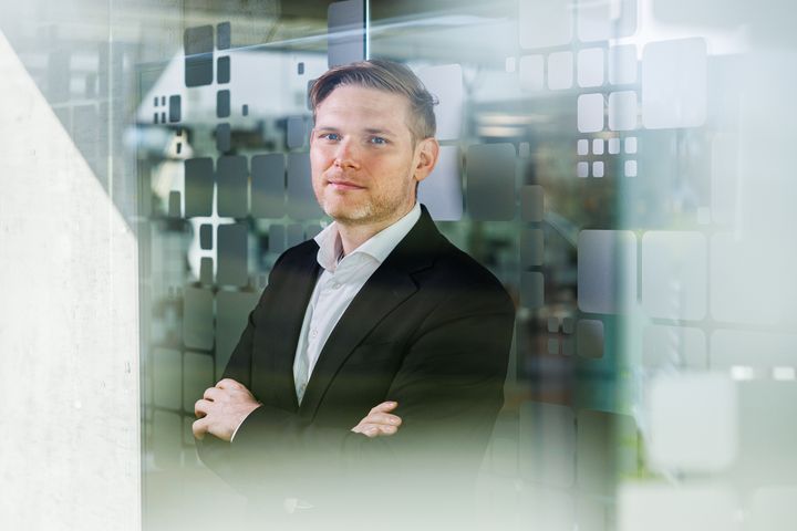 Jacob Rahbek Bach, direktør i NRGi, står i jakkesæt i et kontormiljø.