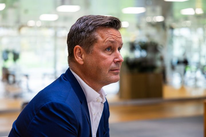 Jacob Schmidt sidder i jakkesæt indendørs.