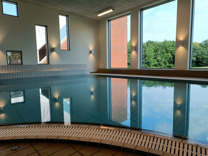 Det store varmtvandsbassin i Ribe Svømmebads nye wellnessafsnit kan nydes med udsigt til grønne omgivelser. Foto: Privat.