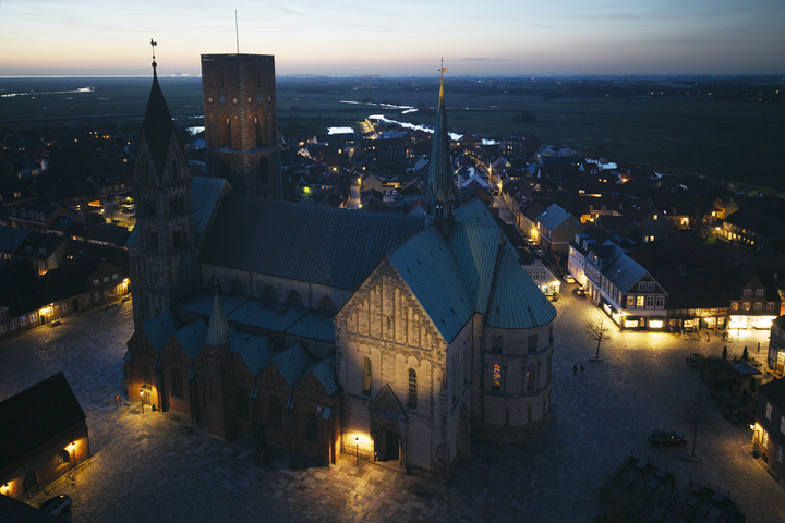 Ribe Domkirke set fra sydøst mod Esbjerg og Vadehavet med prøvebelysning på korsskibets gavl, rytterspiret og en enkelt lyskilde på Borgertårnet.
