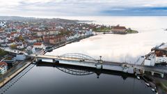 Luftfoto af Sønderborg med en bro over vandet og byens bygninger i baggrunden.