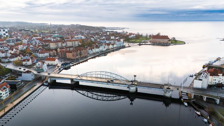 Luftfoto af Sønderborg med en bro over vandet og byens bygninger i baggrunden.