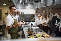 Kok Matt Orlando taler om upcycling af overskudsmad til en gruppe elever i et køkken, mens han viser forskellige retter på bordet.