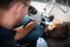 Læge undersøger en patients øre med et specialiseret instrument.