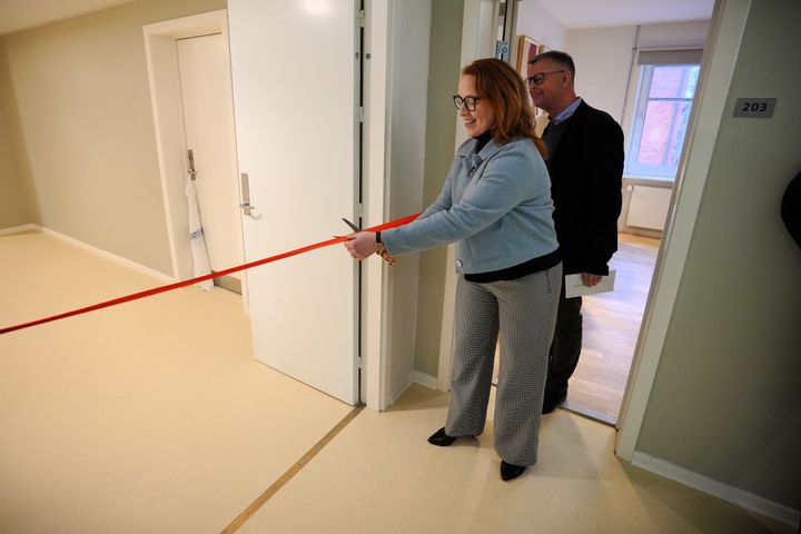 Regionsrådsformanden klipper en rød snor ved indvielsen af nye værelser.
