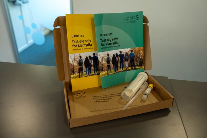 Kasse med testkit til klamydia, indeholdende vejledninger, prøverør, transportrør, svarkuvert og podepind/pipette.