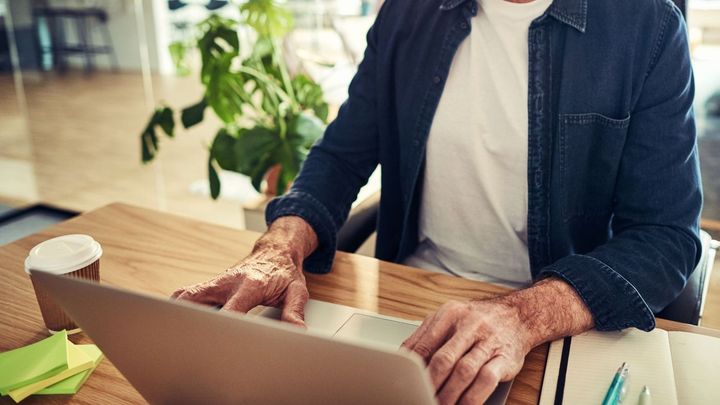 Nærbillede af en ældre mands hænder med bærbar computer