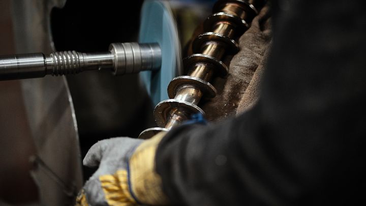 Nærbillede af person med kraftige handsker, som betjener en industrimaskine.