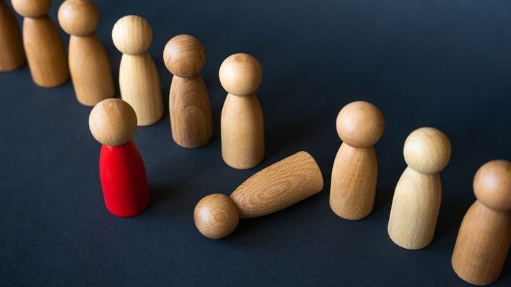 Mange små træfigurer, hvor én er fremhævet i rød (chef), og en af de menige figurer er væltet.