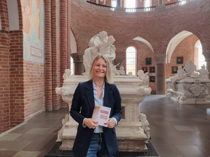 Ny guidebog til Roskilde Domkirke gør det lettere for den besøgende at finde de mange kulturhistoriske og kongelige fortællinger i kirken, der er UNESCO verdensarv. Redaktør og formidlingsansvarlig Sara Peuron-Berg har samtidig sikret, at historier om vigtige kvinder har fået mere plads. Pressefoto/fondsorganisationen bag kulturarven, Roskilde Domkirke.