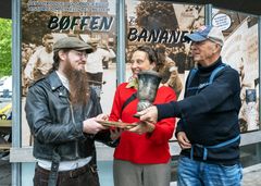 Bøffens børnebørn, Josefine og Joachim Randrup, overdrager deres farfars trofæ og en scrapbog til museumsinspektør Jakob Caspersen. Nu efterlyser Joachim Randrup – længst til højre – efterkommere til Bananen og giver dem mulighed for oprejsning.