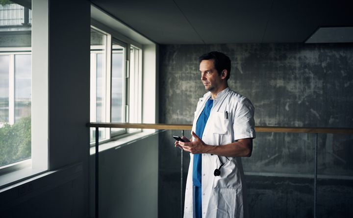 En hospitalsmedarbejder står med sin smartphone i hånden
