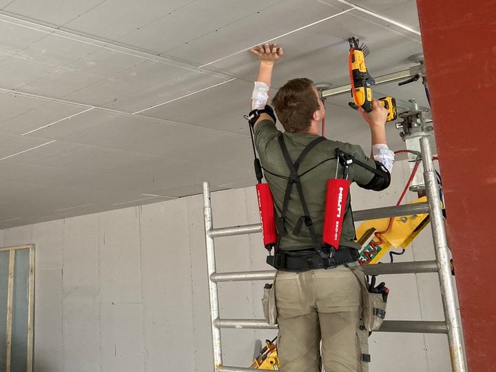 Tømrer iført exoskelet monterer loft
