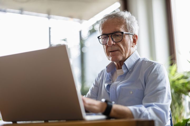 Senior sidder foran computerskærm