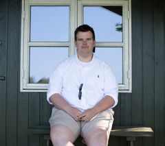 Frederik Broch på 24 år sidder på en bænk foran et vindue. Han har lidt af angst siden gymnasieårene.
