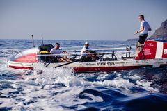En avanceret robåd på havet med tre roere ombord.