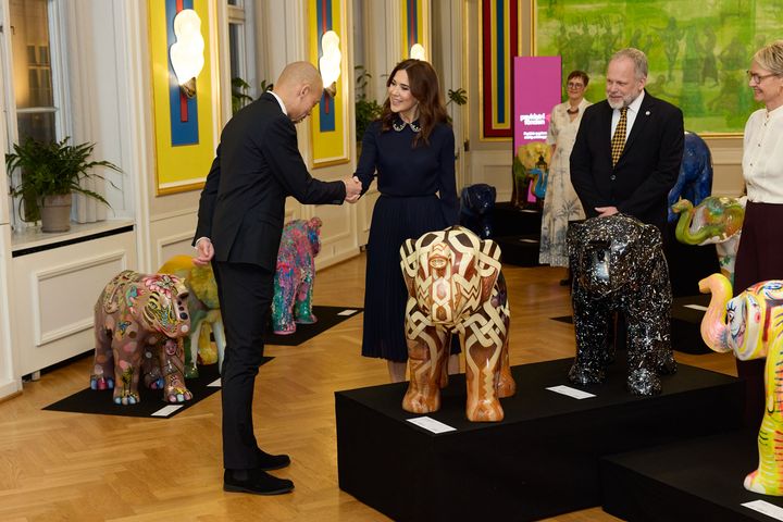 Kunstner Benjamin Abana viser Dronningen sit kunstværk.