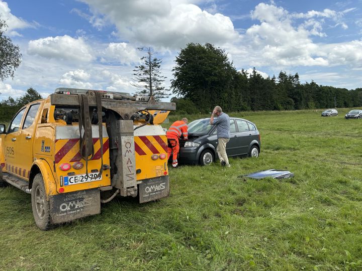 En bil fra SOS Dansk Autohjælp hjælper en bilist med at trække en bil fri fra en mark.