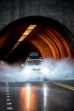 Bil kører gennem vandpyt i tunnel.