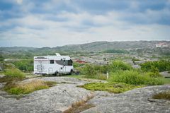 Husbil parkerad i ett naturskönt bergslandskap under en molnig himmel.