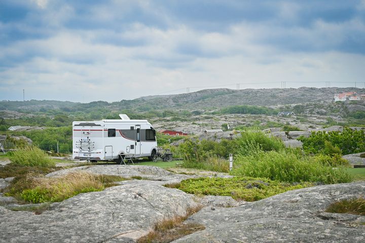 Husbil parkerad i ett naturskönt bergslandskap under en molnig himmel.