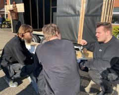 Lukas Byrdal Sørensen (th) taler med sine skolekammerater om, hvordan installationsopgaverne på vognen gribes bedst an. Foto: AARHUS TECH.