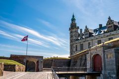 Kronborgs hovedindgang med et dansk flag i baggrunden på en solrig dag