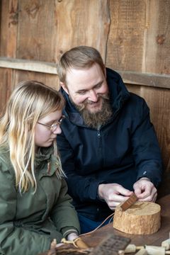 Far og datter laver læderpung i vikingelandsbyen sammen