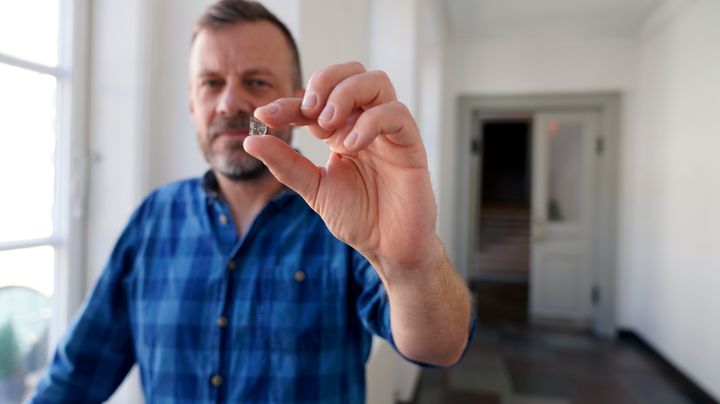 Mads Dengsø Jessen, Senior Researcher at the National Museum of Denmark, with a piece of Window Glass fragment from the Viking Age. Photo: John Fhær Engedal Nissen, the National Museum of Denmark.