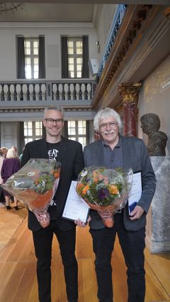 Tim Flohr Sørensen (tv.) modtog rejselegatet, mens Lennart Secher Madsen (th.) modtog hovedprisen, fredag i Nationalmuseets festsal. Foto: Nationalmuseet