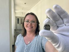 Gitte Tarnow Ingvardson with one of the coins. Photo: John Fhær Engedal Nissen, the National Museum of Denmark.