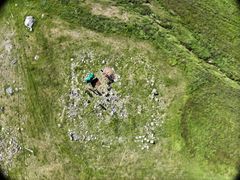 Kirkeruinen set fra oven med udgravning af graven. Yderst anes kirkegårdsmuren, mens kirken er stenhoben i midten. Foto: Aqqaluaq Frederiksen, Kujataa UNESCO World Heritage Site.