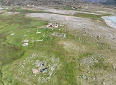 The church ruins are visible in the foreground. The square outer edge that can be seen is the cemetery wall, which surrounds the cemetery and church. The church is the pile of stones in the middle of the square. Photo: Aqqaluaq Frederiksen, Kujataa UNESCO World Heritage Site.
