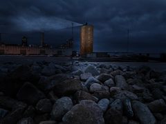 'GENKALD' transformerer Lodstårnet til et fyrtårn, der med søgende bevægelser leder efter nye forbindelser i byen fra sin placering på den gamle havneplads ved Pier 3. Henvendelserne og kommunikationen rettes ikke længere ud mod havnen og havet, men ind mod byen. Lysværket af Elisabeth Holager Lund er en invitation til byens befolkning om at tænke bygningen ind i fremtidens Aarhus.