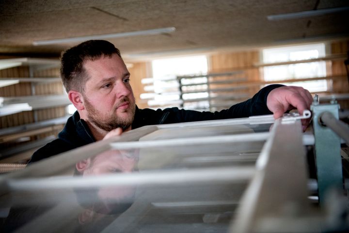 Lasse Thomsen spejler sig i et vindue i værkstedet.