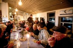 En gruppe mennesker spiser suppe ved et langbord i en hyggelig restaurant.