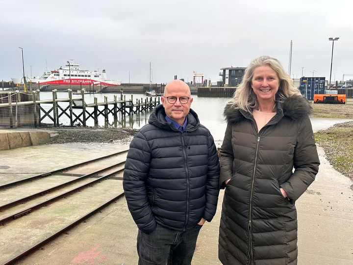 To personer står ved Rømø havn med en færge i baggrunden.