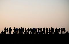 Silhuetter af en gruppe mennesker på en bakke i solnedgang.