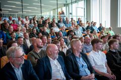 En stor gruppe mennesker sidder sammen i et auditorium og ser fremad med stor opmærksomhed.