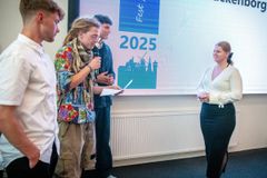En gruppe mennesker på en scene, hvor Årets Lærling/Elev 2025 præsenteres. En person gives en pris.