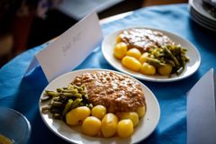 To tallerkener med kartofler, bønner og en brun sauce på en blå dug.