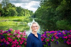 Theresé Andersen, fagchef for Arbejdsmarkedet i Tønder Kommune, smiler og står foran en å og blomster.