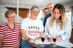 Gruppen skriver under på aftalen ved et bord med champagneglas.