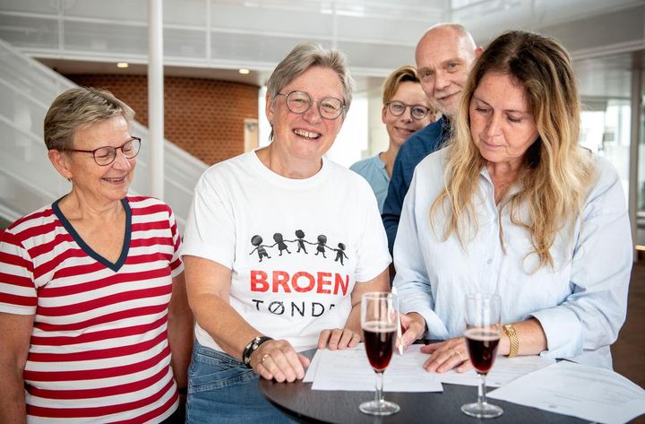Gruppen skriver under på aftalen ved et bord med champagneglas.