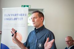 En mand holder en præsentation foran en roll-up med teksten "Bliv partner i ungeløftet".