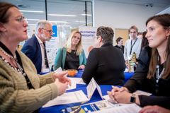 Et gruppe mennesker står ved en stand og diskuterer under en messe.