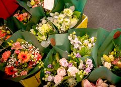 Buketter af forskellige blomster med grøn indpakning.