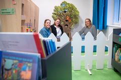 Tre kvinder sidder i et børneområde på biblioteket med legetøj og bøger omkring dem.